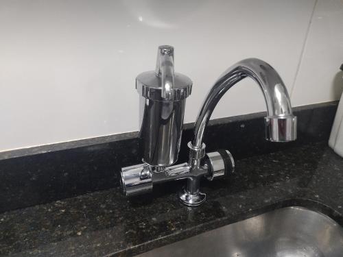 Un fregadero de cocina con un grifo sobre una encimera en Ap Frente Mar, wi-fi, piscina, pet, check-in e check-out flexíveis, en Praia Grande