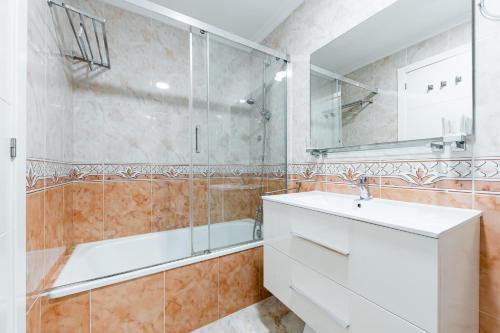 een badkamer met een wastafel, een bad en een spiegel bij Playa del Pinet Apartment in La Marina