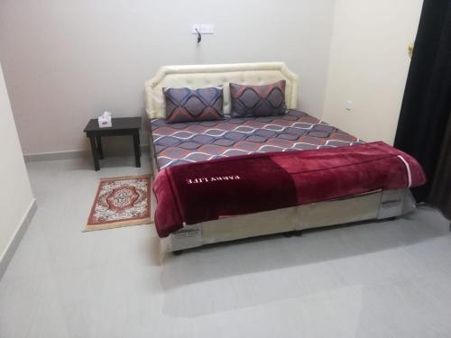um quarto com uma cama grande e um cobertor vermelho em APARTMENTS HOQANI em Salalah