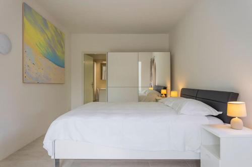 a large white bed in a white bedroom at Immersi nella natura con accesso al fiume maggia in Locarno