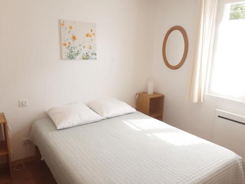 1 dormitorio con cama blanca y espejo en la pared en Le chemin de Bruniele, en Aubres