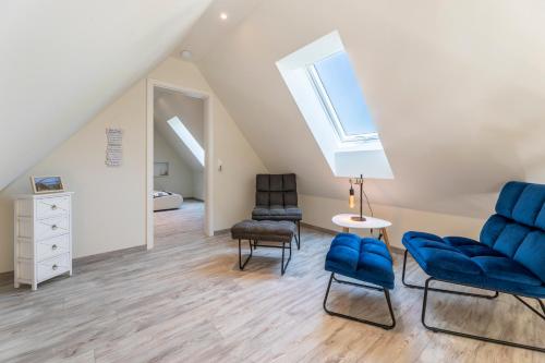a attic living room with blue chairs and a window at Haus Hamburg Wohnung 2 in Hohwacht