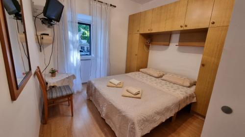 a small bedroom with a bed and a small table at Sobe Biserka i Mario Brseč in Brseč