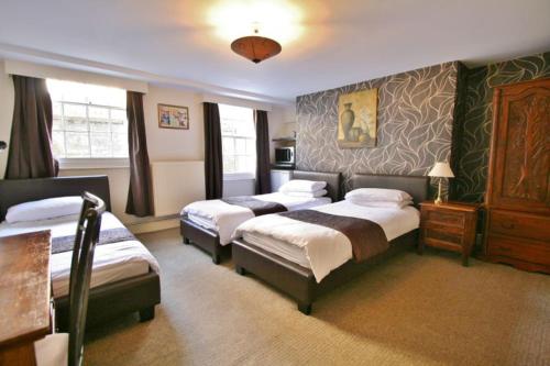 ein Hotelzimmer mit 3 Betten in einem Zimmer in der Unterkunft Central Hotel Cheltenham by Roomsbooked in Cheltenham