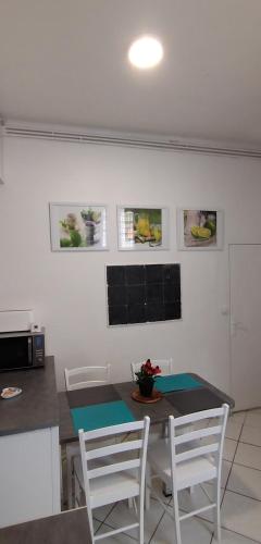 une cuisine avec une table, des chaises blanches, une table et un comptoir dans l'établissement Appartement de ville, à Nantes