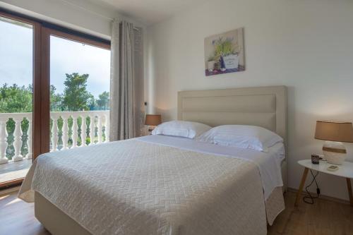 a white bedroom with a bed and a balcony at Apartments Emanuela in Sukošan