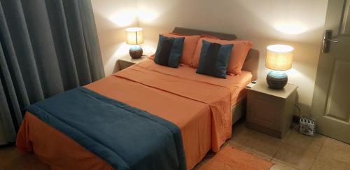 ein Schlafzimmer mit einem Bett mit orangefarbener Bettwäsche und zwei Lampen in der Unterkunft Paradya Beach Apartments in Flic-en-Flac