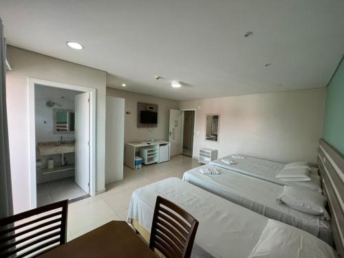 a hotel room with two beds and a bathroom at Recanto Armação Pousada in Penha