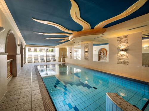 a large swimming pool with a ceiling with antlers at Hotel Alpina in Ried im Zillertal