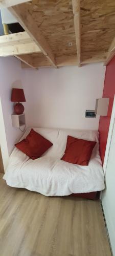 Cama en habitación pequeña con almohadas rojas en Le séchoir, gite du XVIII siècle, jacuzzi privatif en Carsac-Aillac