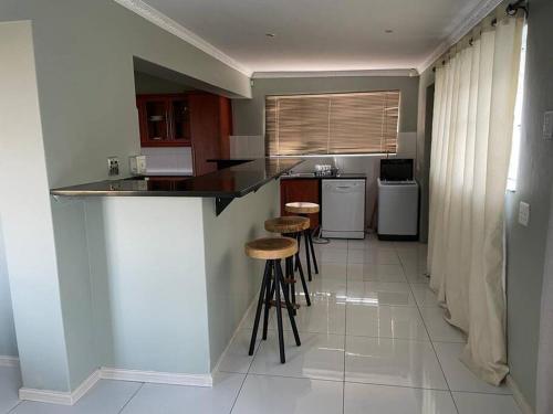 a kitchen with a counter and stools in it at 15 St Aidans in Grahamstown