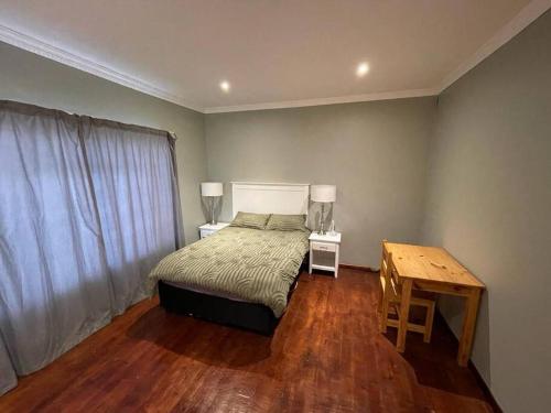 Schlafzimmer mit einem Bett und einem Holztisch in der Unterkunft 15 St Aidans in Grahamstown