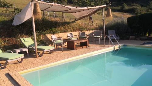 a swimming pool with chairs and an umbrella and a table and chairs at Casa rural La Frambuesa in Galaroza