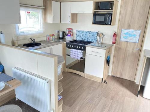 a small kitchen with a stove and a microwave at Prime Location & Luxurious Hot Tub in Tattershall