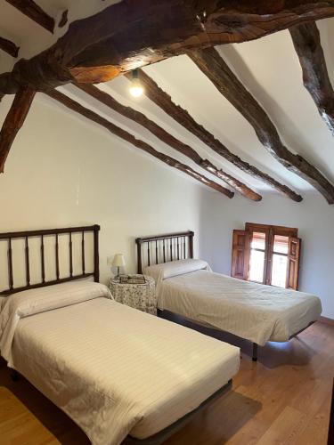 two beds in a room with wooden beams at Casa Rural Aras Apartamentos Turísticos in Aras de Olmos