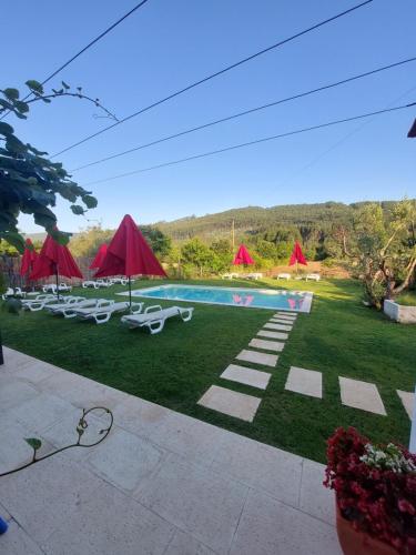 a pool with chairs and umbrellas in a yard at Sotam Country House EN342 in Góis