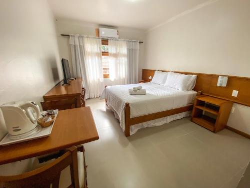 a hotel room with a bed and a desk and a television at Pousada Villa Verde in Canela