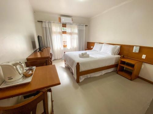 Habitación de hotel con cama, escritorio y TV. en Pousada Villa Verde, en Canela