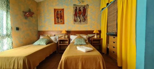 2 camas en una habitación con paredes amarillas y azules en Casa Vargas en Pedrezuela