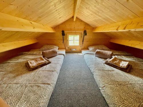 um quarto com 3 camas num chalé de madeira em Piejūras Kaķīšu namiņš em Ķesterciems