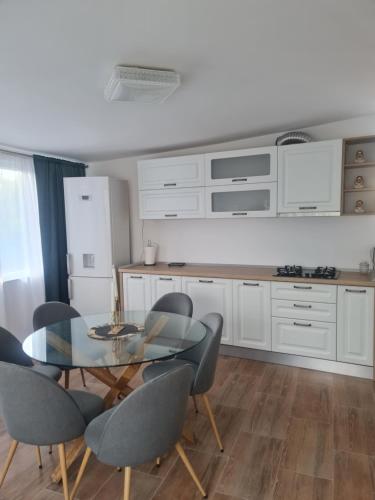 una cocina con mesa de cristal y sillas. en Casa Ap Dayana, en Eforie Sud