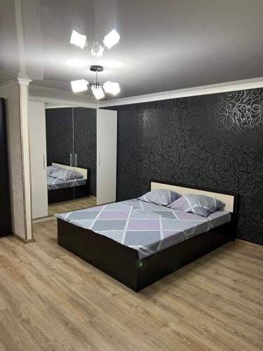a bedroom with a large bed and a mirror at Квартира в районе набережной in Balqash
