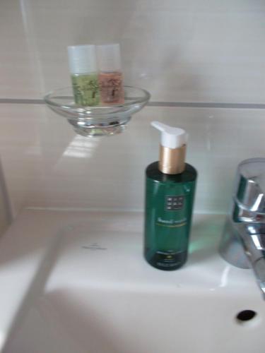 una botella verde de jabón en el lavabo del baño en Ferienwohnung Jürges, en Northeim