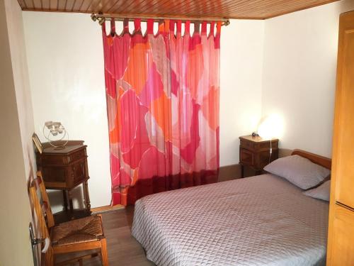 1 dormitorio con cama y cortina roja en RANDO BAIN CUEILLETTE Profitez des CÉVENNES, en Chamborigaud