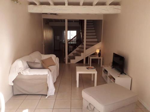a living room with a white couch and a tv at gite au village in Mourvilles-Hautes