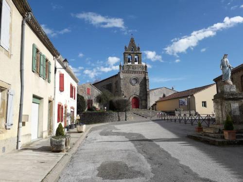 an empty street with a church with a clock tower at gite au village in Mourvilles-Hautes