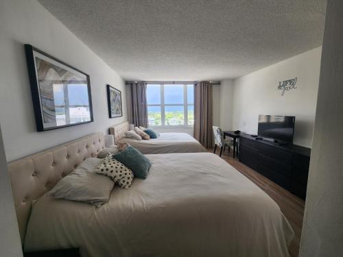 una camera d'albergo con due letti e una televisione di Entire Beach Front Condo w/ pool Amazing view 4pax a Miami Beach