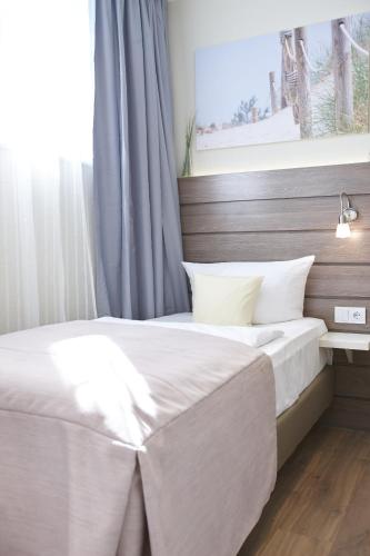 a bedroom with a white bed with a window at Hotel Kiel by Golden Tulip in Kiel