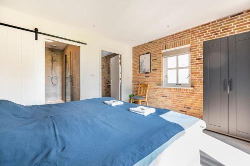 een slaapkamer met een blauw bed en een bakstenen muur bij Gastsuite Foar elkoar Hilaard. in Hijlaard