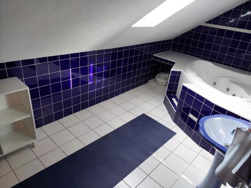 a blue tiled bathroom with a sink and a tub at Apartmán Tatiana in Smižany