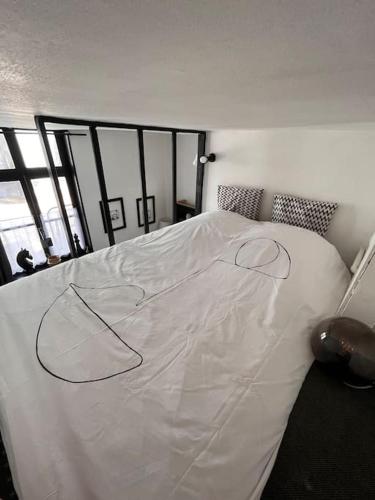 un grand lit blanc dans une pièce avec des fenêtres dans l'établissement Au cœur du VIEUX-LILLE : Charmant appartement, à Lille