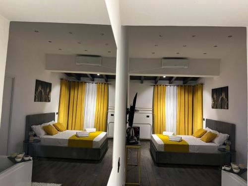 パレルモにあるFUDDIA Room & Suiteの黄色いカーテンが備わる客室のベッド2台