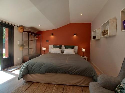 1 dormitorio con 1 cama grande y pared de color naranja en Shanti Home, en La Tour-sur-Orb
