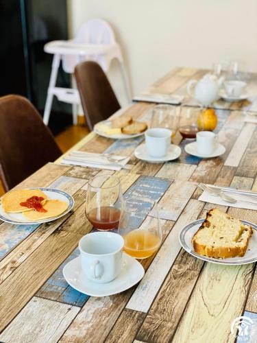 a wooden table with plates of food and drinks on it at Le Coq du Nord - Mailhac Gîte et Chambres d'Hôtes in Mailhac