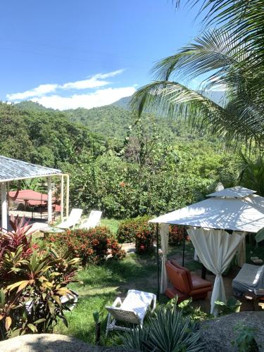 a patio with chairs and an umbrella and a mountain at Kimara Tayrona Hostel in El Zaino