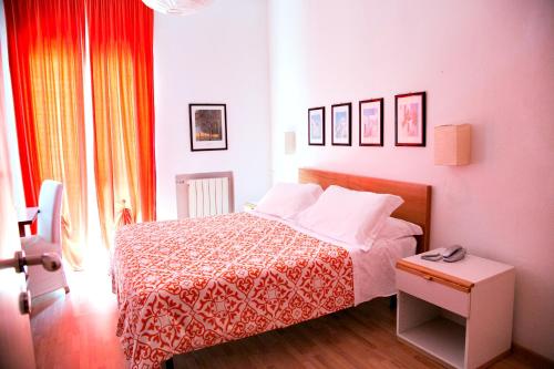 a bedroom with a bed with a red and white blanket at Hotel Kinda in Castiglione della Pescaia