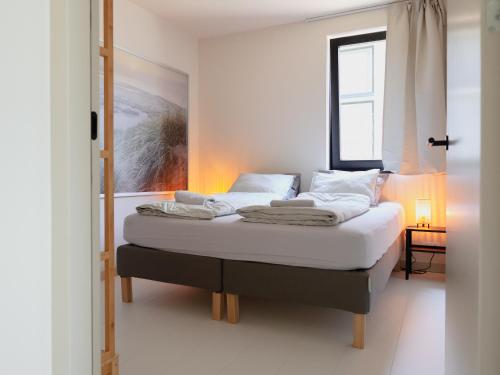 Schlafzimmer mit einem Bett mit weißer Bettwäsche und einem Fenster in der Unterkunft Zilt aan Zee in Egmond aan Zee
