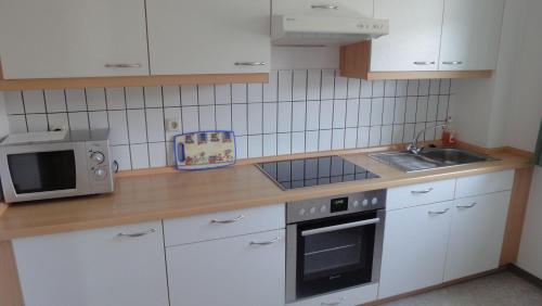 a kitchen with white cabinets and a microwave and a sink at Ferienwohnung-Hafenblick-Ueckermuende-Stettiner-Haff-Ostsee in Ueckermünde