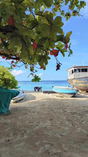 a boat on the beach next to the ocean at Bird Beak Beach in Omadhoo