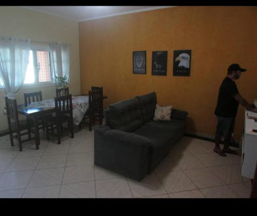 a man standing in a living room with a couch at Hostel Ariel Beach Pousada in Mongaguá
