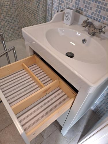 un lavabo con una estantería de madera debajo en Terrazza Santoro per la vostra estate da sogno!!! en Vieste