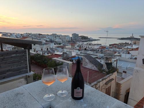 een fles wijn en twee wijnglazen op een richel bij Terrazza Santoro per la vostra estate da sogno!!! in Vieste