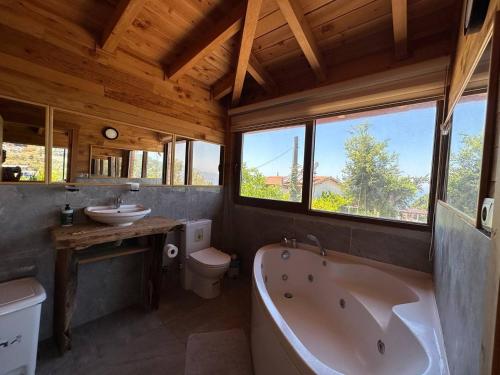 a bathroom with a tub and a toilet and a sink at Faralya Villa in Fethiye