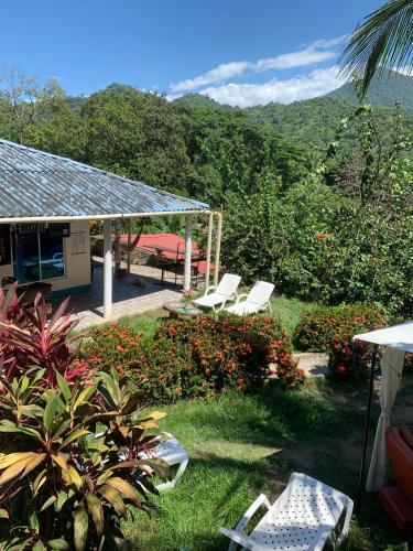 a group of white chairs sitting in a yard at Kimara Tayrona Hostel in El Zaino