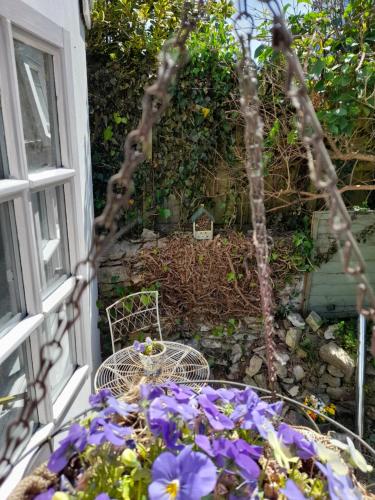 a table and chair on a balcony with purple flowers at My Little Studio in Farmborough