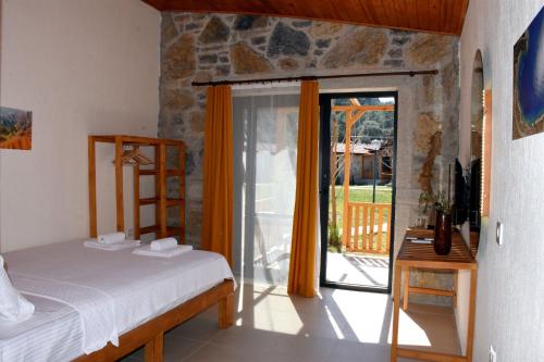 - une chambre avec un lit et une porte coulissante en verre dans l'établissement Begonvillage Tatil Evleri, à Datça